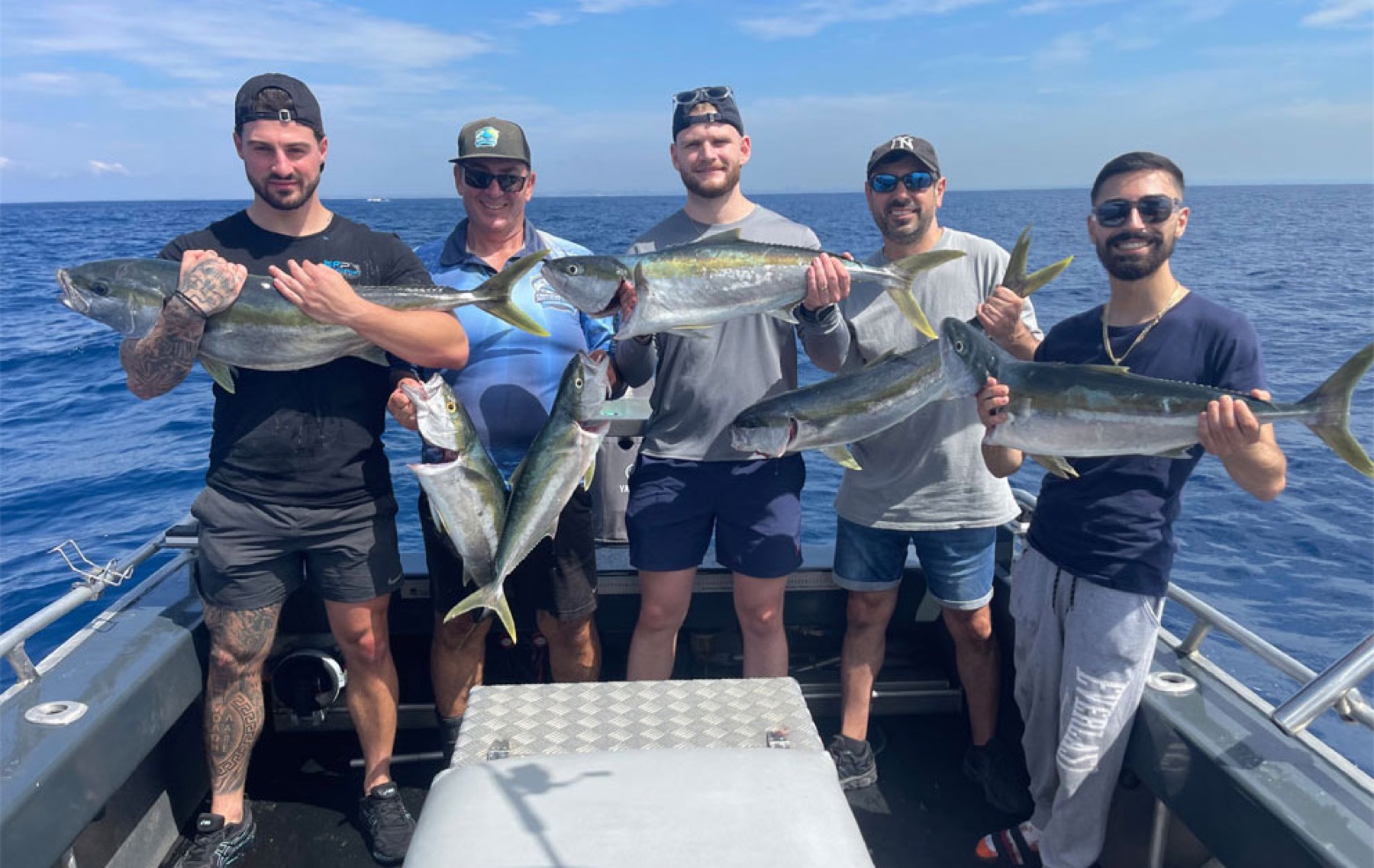 Five anglers holding kingfish on the deck off Botany Bay
